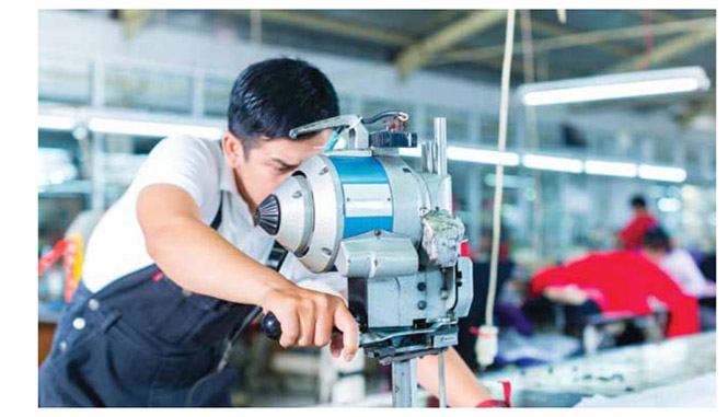 Image of worker operating assembly-line equipment